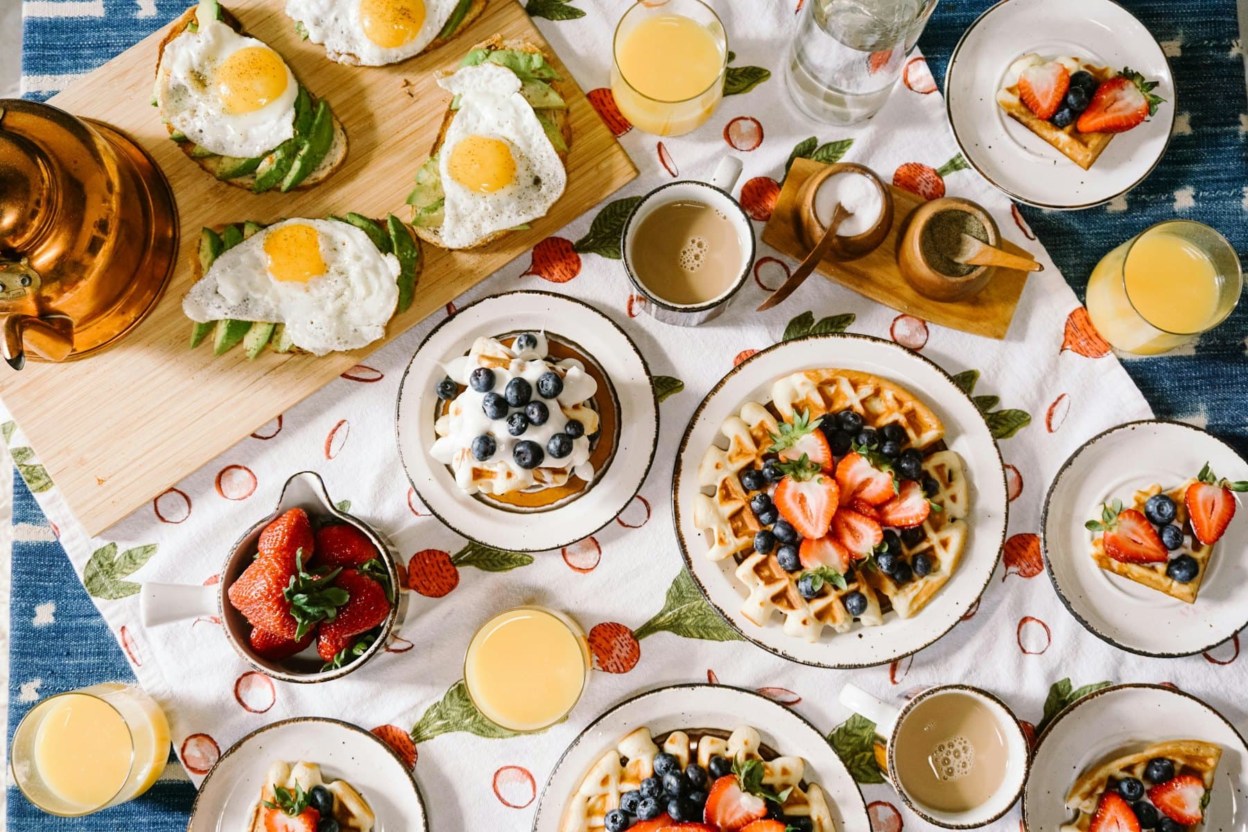 A brunch table with waffles, eggs and juices